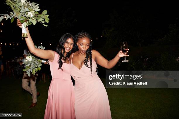 happy multiracial bridesmaids dancing at reception - bruidsmeisje stockfoto's en -beelden