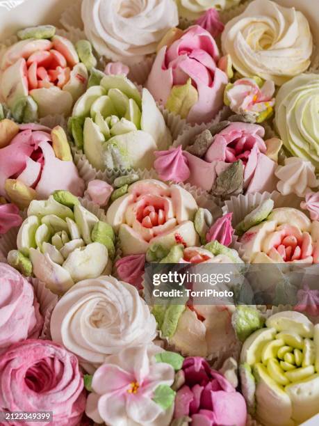 close-up rose-shaped pastries in pink and yellow colors. many roses made from marshmallows. colorful marshmallow rosettes. zefir or zephyr flowers in the style of shabby chic - gelatin powder stock-fotos und bilder