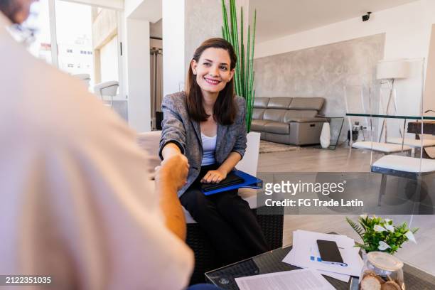 real estate agent shaking hand of a customer on a meeting at home - ethnic millennial real estate stockfoto's en -beelden