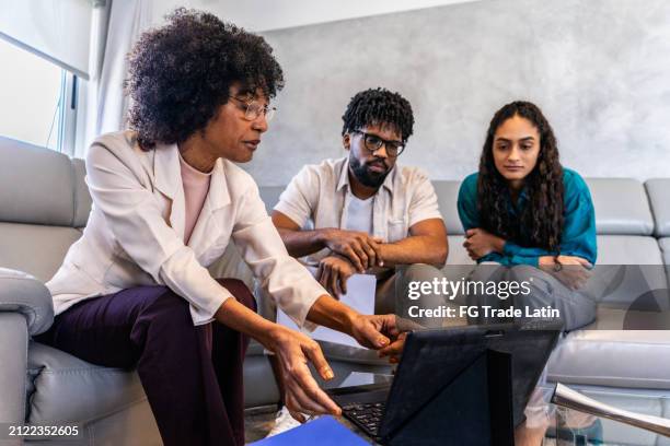 financial advisor doing a meeting with young couple at home - antilles stock pictures, royalty-free photos & images