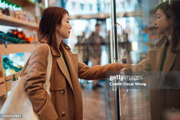 young asian woman shopping in grocery store with reusable shopping bag - task list stock pictures, royalty-free photos & images