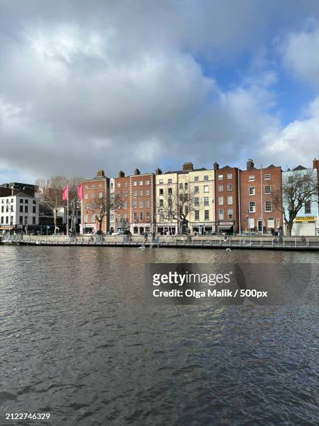 view of buildings by river against cloudy sky,dublin,ireland - leinster province stock pictures, royalty-free photos & images