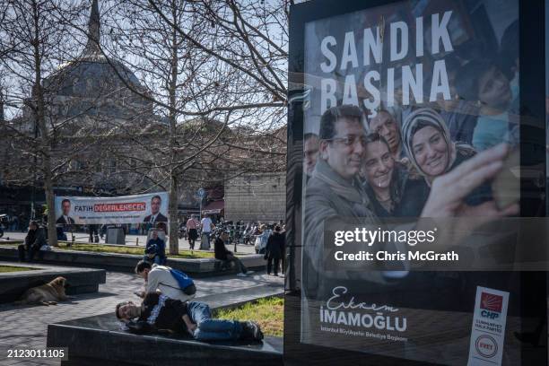 Man sleeps behind a campaign poster of Ekrem Imamoglu, Istanbul Mayor and the Republican People's Party candidate for reelection ahead of the local...