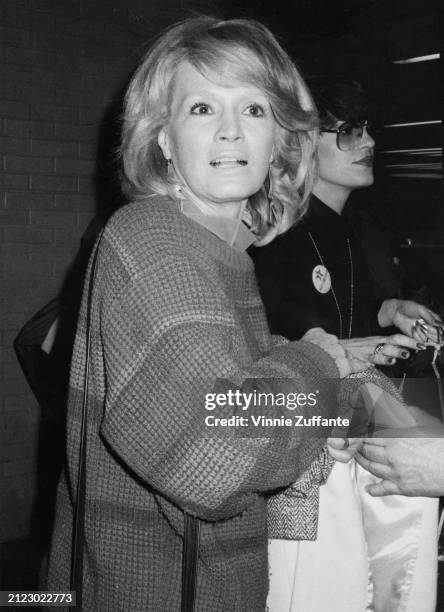 American actress Angie Dickinson wearing a sweater, with her coat over her arm, arrives in New York to attend the 'Night of 100 Stars II Gala', held...