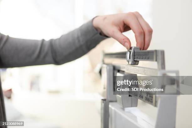 close-up unrecognizable woman adjusting beam scale in doctor's examination room - fazer dieta imagens e fotografias de stock