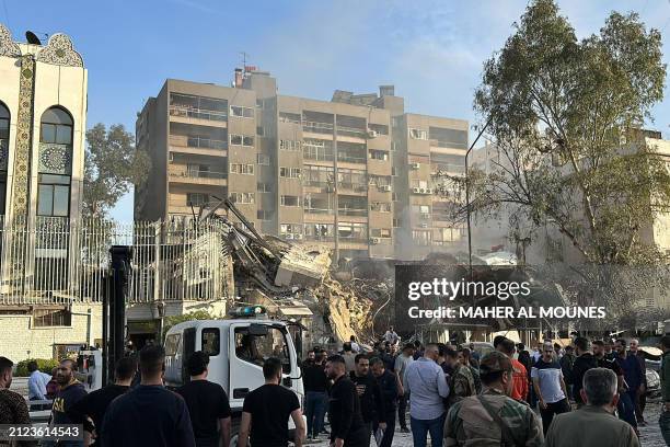 Emergency and security personnel gather at the site of strikes which hit a building next to the Iranian embassy in Syria's capital Damascus, on April...