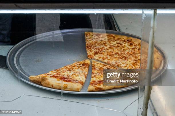 Closeup at a pizza pie with slices, inside a 99 cent pizza shop with the logo inscription 99c Fresh Pizza, also known as dollar slice in Manhattan,...