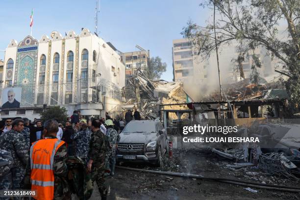 Emergency and security personnel inspect the site of strikes which hit a building annexed to the Iranian embassy in Syria's capital Damascus, on...