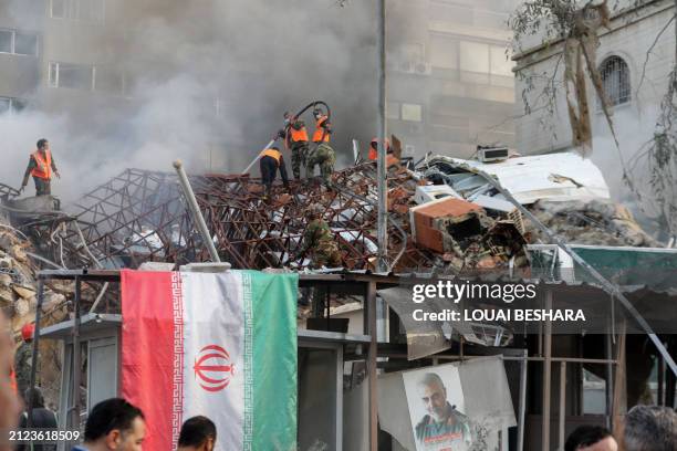 Emergency and security personnel extinguish a fire at the site of strikes which hit a building annexed to the Iranian embassy in Syria's capital...