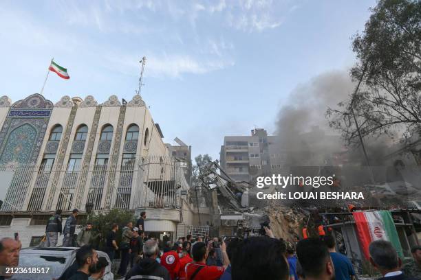 Emergency and security personnel search the rubble at the site of strikes which hit a building annexed to the Iranian embassy in Syria's capital...