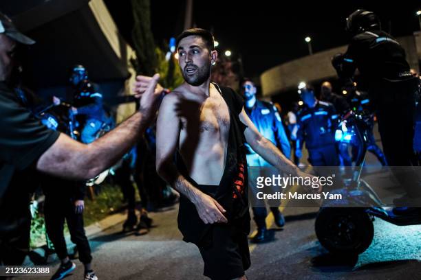Protester is told to step away from the road by the police as they work to remove others from blocking a roadway during an anti-government...