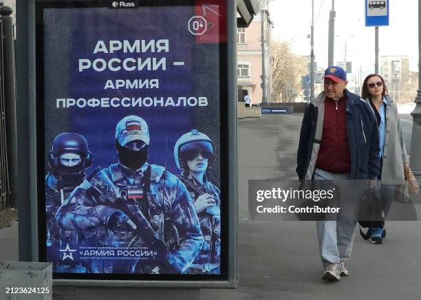 People walk past a billboard with militaristic propaganda, installed on the bus stop, April 1 in Moscow, Russia. The sign reads: "Army of Russia is...