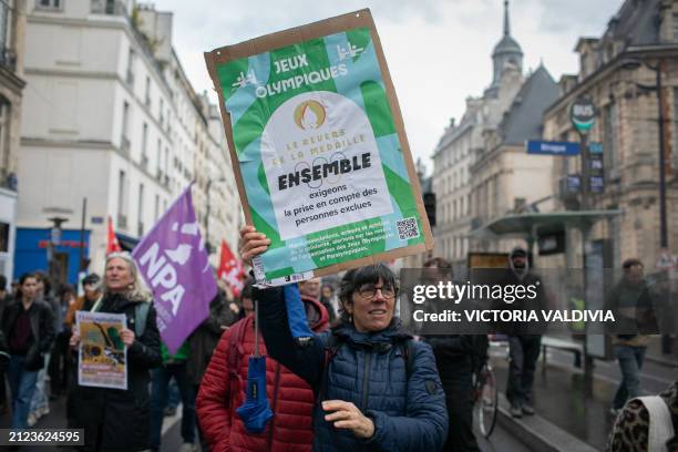 Demonstrator holds a banner that reads "Olympic Games, the other side of the coin" at the European mobilization for housing to mark the end of the...