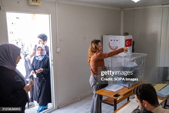 A voter casts her vote in a ballot box at a polling station during ...