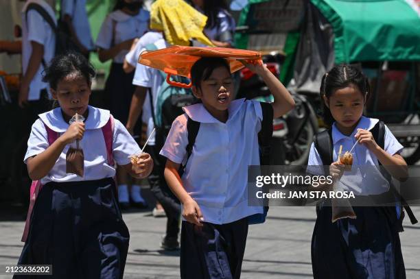 Student uses an envelop to protect herself from the sun during a hot day in Manila on April 2, 2024. More than a hundred schools in the Philippine...