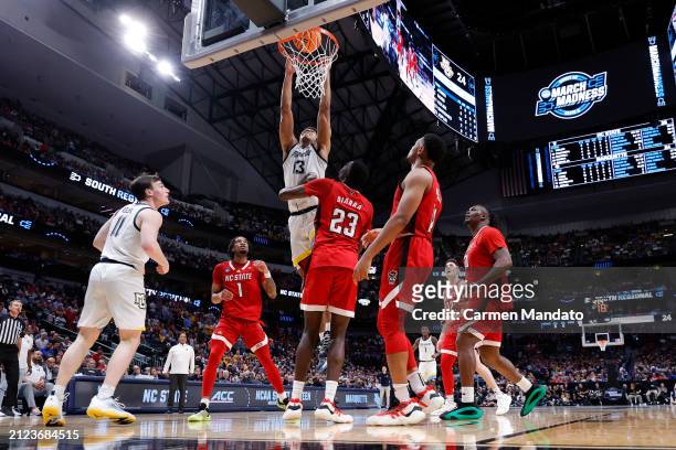 Oso Ighodaro of the Marquette Golden Eagles dunks over Jayden Taylor and Mohamed Diarra of the North Carolina State Wolfpack during the first half of...