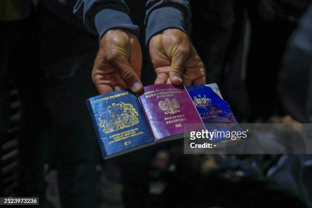 Graphic content / A man displays British, Polish, and Australian passports next to the bodies of World Central Kitchen workers at Al-Aqsa Hospital in...
