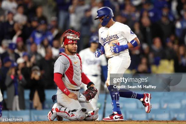 Miguel Rojas of the Los Angeles Dodgers touches home plate after hitting a solo homerun as Willson Contreras of the St. Louis Cardinals looks on...