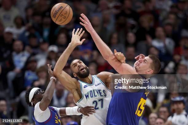 Rudy Gobert of the Minnesota Timberwolves is stripped of the ball by Reggie Jackson and Nikola Jokic of the Denver Nuggets during the third quarter...
