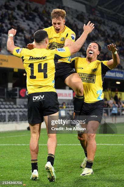 Josh Moorby of the Hurricanes celebrates with Ruben Love and Billy Proctor after scoring a try during the round six Super Rugby Pacific match between...