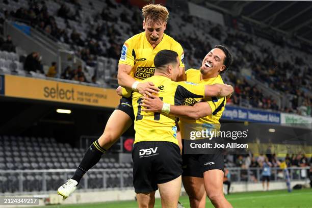 Josh Moorby of the Hurricanes celebrates with Ruben Love and Billy Proctor after scoring a try during the round six Super Rugby Pacific match between...