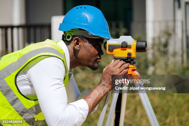 engineer is using a survey camera to measure levels on a construction site. - land surveyor stock pictures, royalty-free photos & images