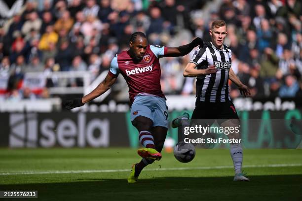 Michail Antonio of West Ham shoots top score the first West Ham goal watched by Emil Krafth of Newcastle during the Premier League match between...