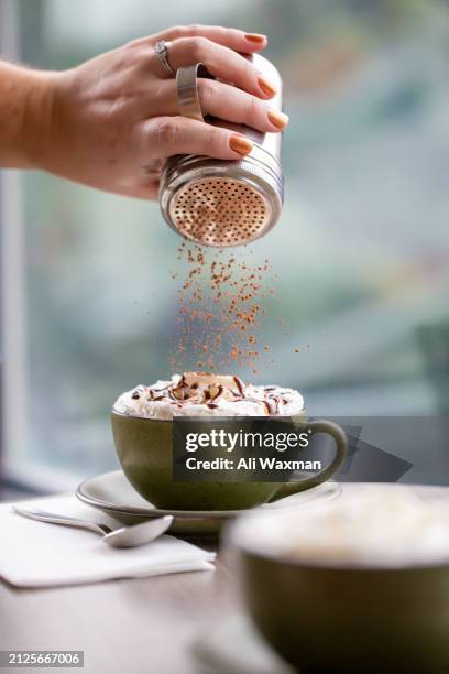 zimt auf einen café-mokka streuen - streuen stock-fotos und bilder