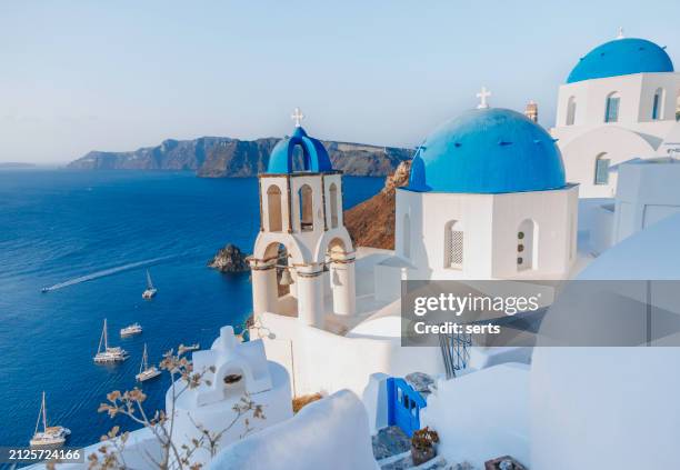 beautiful summer vacation landscape of iconic blue domed churches along the caldera edge at sunny morning against clear blue sky in oia, santorini, caldera, greek islands, greece - mediterranean-blue-roof-santorini stock pictures, royalty-free photos & images