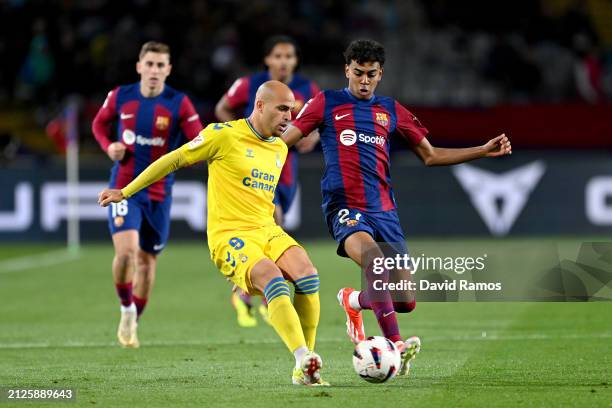 Sandro Ramirez of UD Las Palmas passes the ball whilst under pressure from Lamine Yamal of FC Barcelona during the LaLiga EA Sports match between FC...