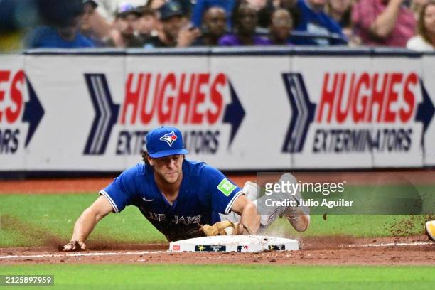 Ernie Clement of the Toronto Blue Jays slides to third base to make the tag before Jose Caballero of the Tampa Bay Rays in the third inning at...