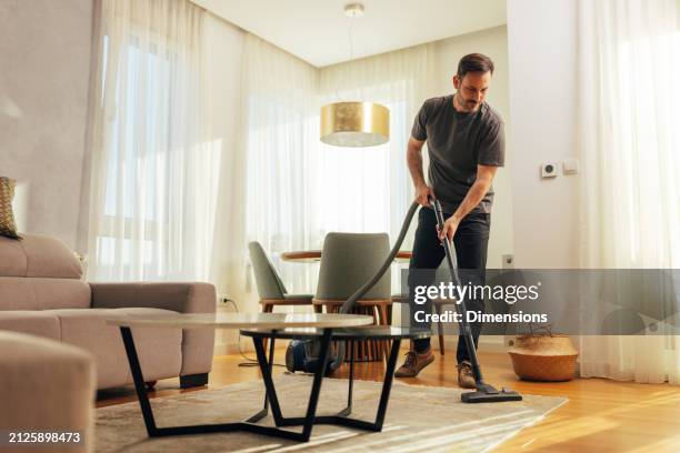uomo aspirapolvere soggiorno - aspirapolvere foto e immagini stock