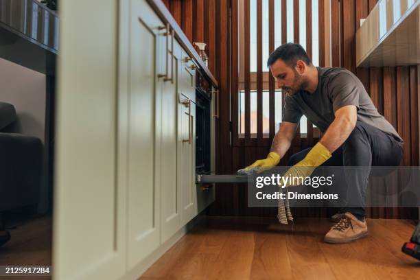 man crouching to clean oven's interior - clean oven stock pictures, royalty-free photos & images