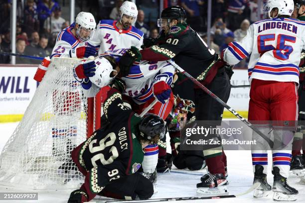 Logan Cooley and J.J. Moser of the Arizona Coyotes push Jack Roslovic of the New York Rangers in front of the net during the first period at Mullett...