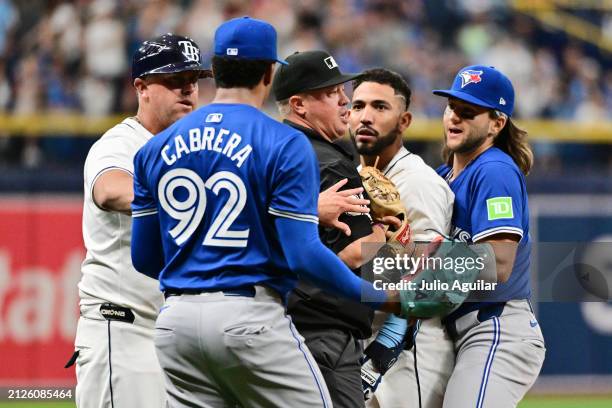 Umpire Cory Blaser stands between Jose Caballero of the Tampa Bay Rays and Genesis Cabrera of the Toronto Blue Jays after a dugout clearing shove in...