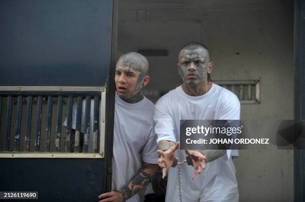 Mara 18 leader Jose Daniel Galindo, aka "Criminal" and gang member Alex Daniel Ramires, aka "Smile", gesture from inside a police armoured security...