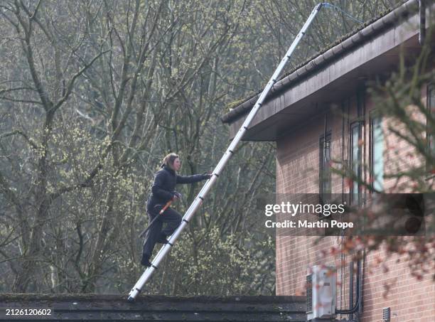Palestine Actionist scales a ladder onto a higher roof carrying a sledge hammer during their protest to highlight Teledyne's collusion with the...