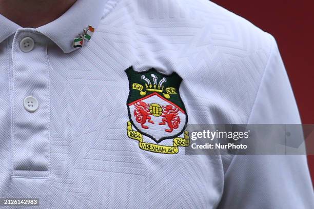 James McClean of Wrexham is displaying the Wrexham badge on his shirt, along with a pin badge featuring the Palestine and Ireland flags, during the...