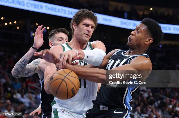 Brook Lopez of the Milwaukee Bucks draws a foul as he battles for a rebound against De'Andre Hunter and Vit Krejci of the Atlanta Hawks during the...
