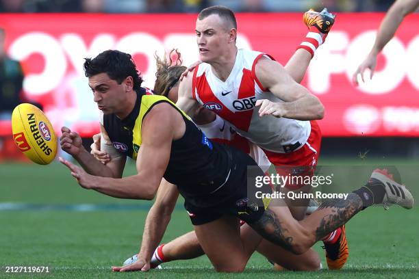 Tim Taranto of the Tigers handballs whilst being tackled by Chad Warner of the Swans during the round three AFL match between Richmond Tigers and...