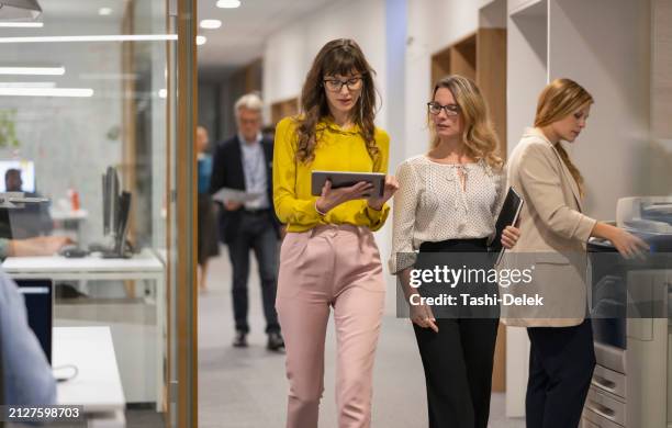 kollegen, die sich unterhalten und im büroflur spazieren gehen - korridor stock-fotos und bilder