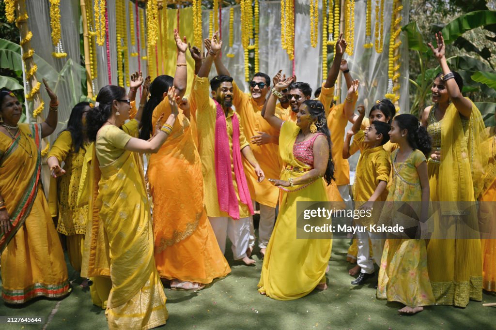 La famiglia e gli amici ballano con la sposa e lo sposo durante la loro cerimonia haldi