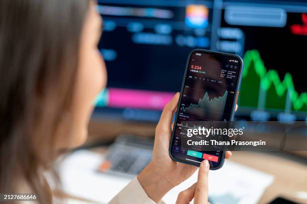 woman buying cryptocurrency through mobile phone app - bitcoin stock pictures, royalty-free photos & images
