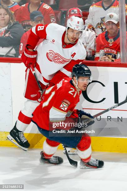 Ben Chiarot of the Detroit Red Wings xand Nick Cousins of the Florida Panthers skate along the boards at the Amerant Bank Arena on March 30, 2024 in...