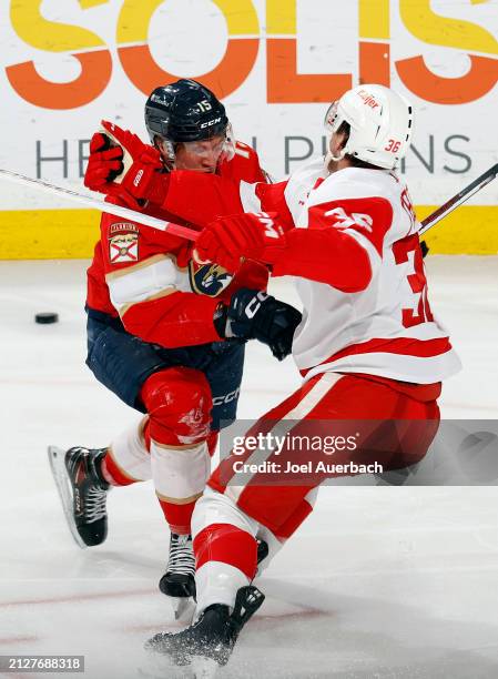 Christian Fischer of the Detroit Red Wings hits Anton Lundell of the Florida Panthers at the Amerant Bank Arena on March 30, 2024 in Sunrise, Florida.