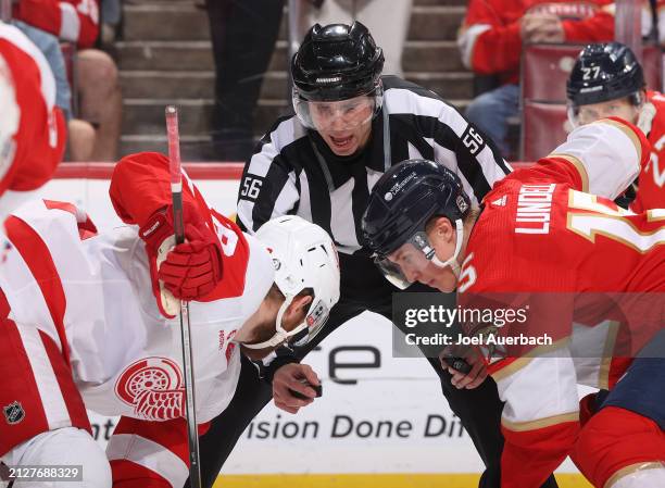 Linesman Julien Fournier drops the puck between Anton Lundell of the Florida Panthers and Ben Chiarot of the Detroit Red Wings at the Amerant Bank...