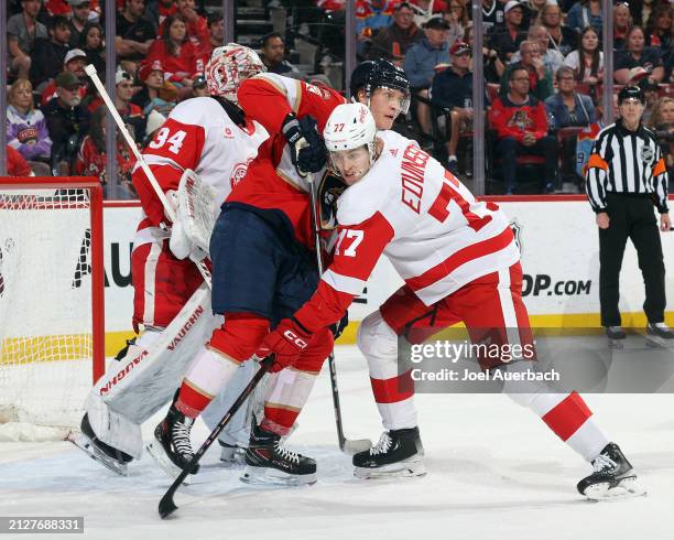 Simon Edvinsson of the Detroit Red Wings defends against Anton Lundell of the Florida Panthers in front of goaltender Alex Lyon at the Amerant Bank...