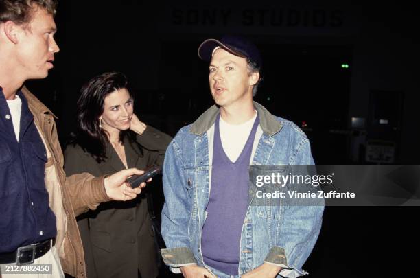 American actress Courteney Cox, wearing a black outfit, and American actor Michael Keaton, who wears a denim jacket over a blue v-neck sweater and a...