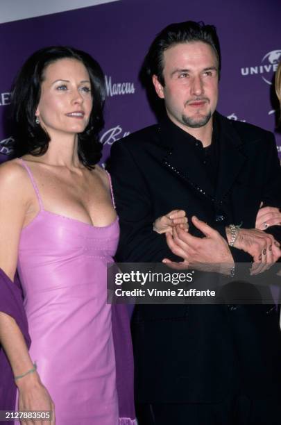 American actress Courteney Cox, wearing a pink dress, arm in arm with American actor David Arquette, who wears a black suit, at the 9th Annual Fire &...