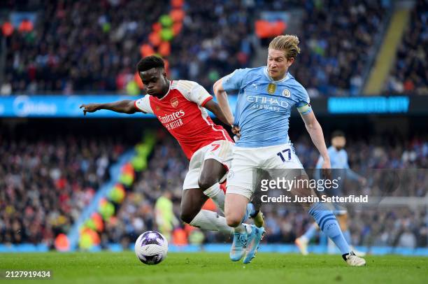 Bukayo Saka of Arsenal battles for possession with Kevin De Bruyne of Manchester City during the Premier League match between Manchester City and...